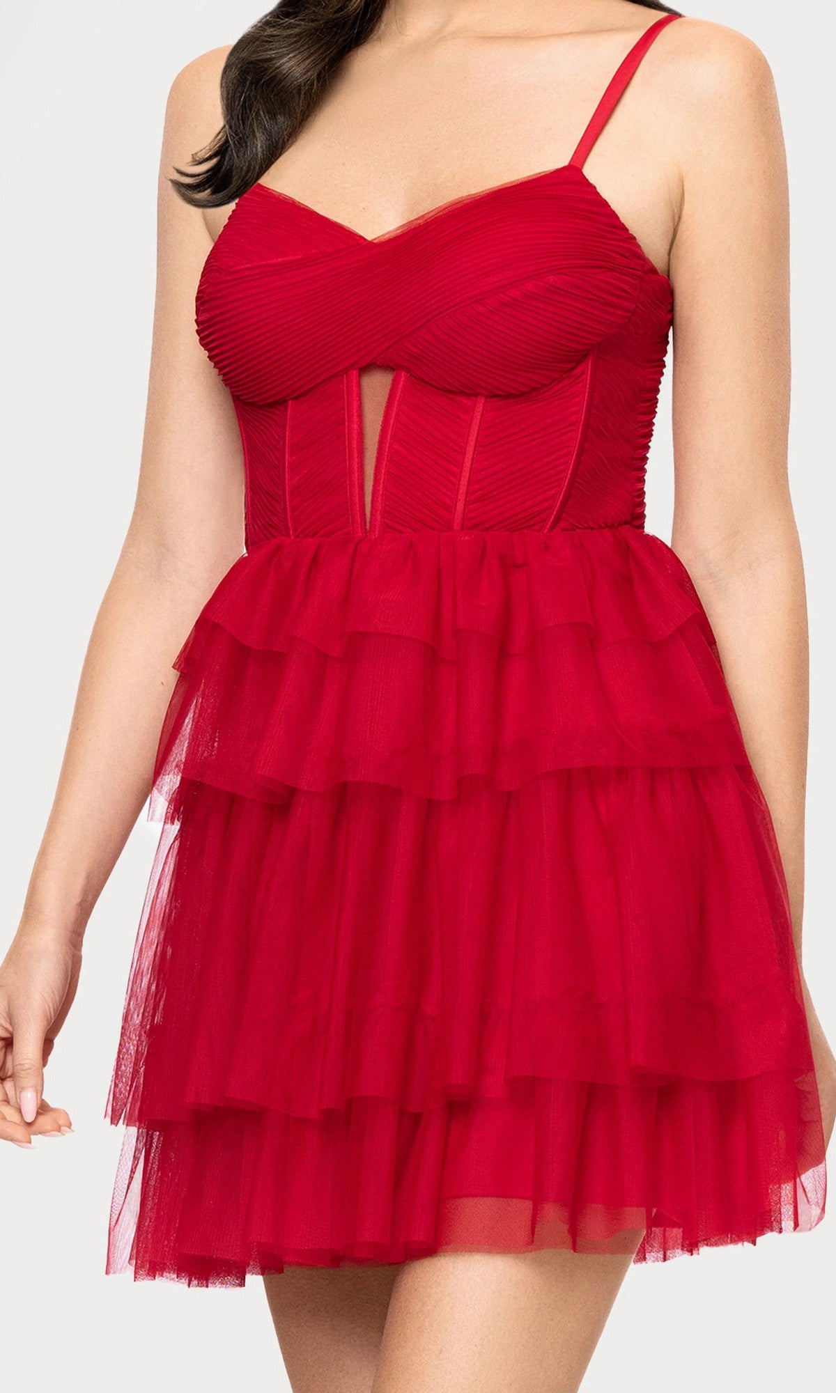 Woman wearing the Blondie Nites 5842BN short prom dress with a sleeveless, fitted red design, ruched mesh corset bodice, sweetheart neckline, and layered tulle fit-and-flare skirt.